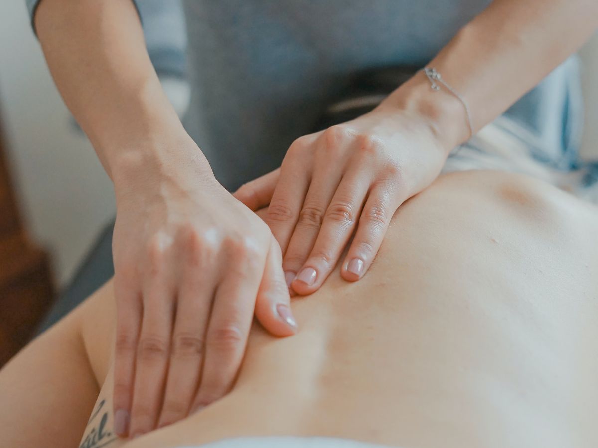 A person is receiving a back massage from another person who is using both hands to apply pressure along the spine.