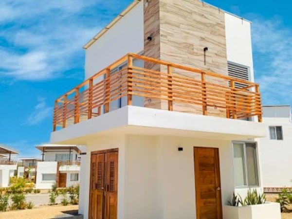This image shows a modern two-story house with wooden railings and doors, featuring a combination of white and natural wood exterior elements under a clear sky.